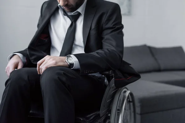 Обрізаний вид інваліда в чорному костюмі, сидячи в інвалідному кріслі з поклонінням голові — стокове фото