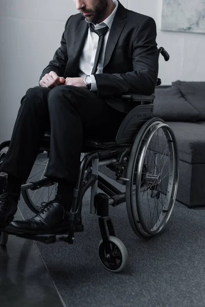 Vue recadrée de l'homme barbu handicapé en costume noir assis en fauteuil roulant — Photo de stock