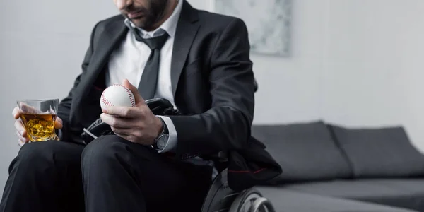 Panoramic shot of disabled man in wheelchair holding ball and glass of whiskey — Stock Photo