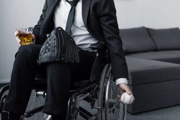 Teilbild eines behinderten Mannes im Rollstuhl mit Tasche auf dem Knie, während er Ball und Glas Whiskey in der Hand hält — Stockfoto