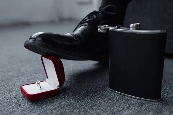 Partial view of man trampling gift box with ring near flask on floor — Stock Photo