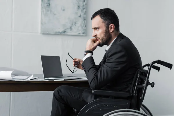 Enttäuschter behinderter Geschäftsmann sitzt im Rollstuhl am Arbeitsplatz — Stockfoto
