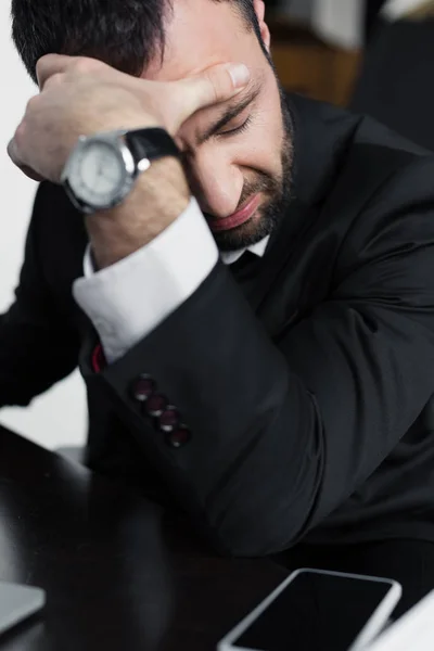 Selective focus of depressed businessman sitting at workplace with closed eyes — Stock Photo