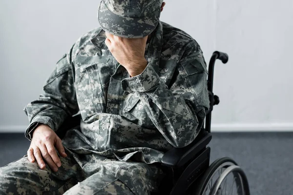Deprimido deficiente homem em uniforme militar sentado em cadeira de rodas e de mãos dadas face a face — Fotografia de Stock