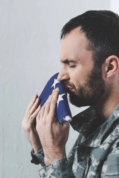 Deprimido barbudo militar homem chorando enquanto beija EUA bandeira nacional — Fotografia de Stock