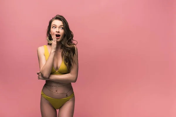 Shocked young woman in yellow swimsuit looking away isolated on pink — Stock Photo