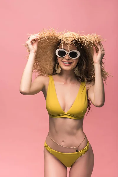 Encantadora chica en sombrero de paja y gafas de sol sonriendo aislado en rosa - foto de stock