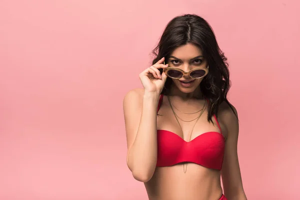 Vorderansicht einer lächelnden attraktiven Frau in Badeanzug und Sonnenbrille isoliert auf rosa — Stockfoto