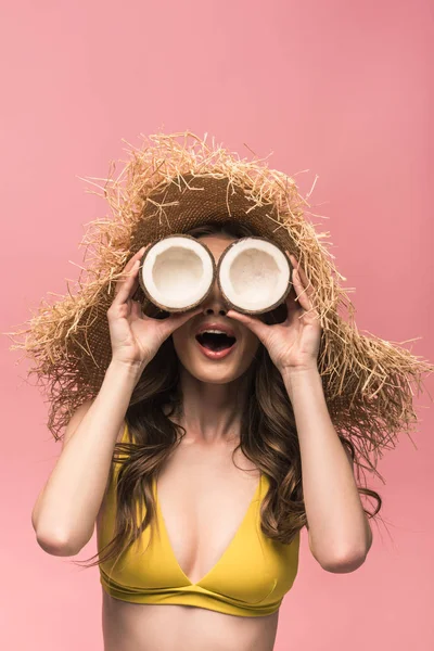 Allegra ragazza in cappello di paglia che tiene le noci di cocco isolate su rosa — Foto stock