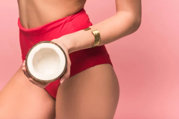 Corte vista de mulher em calcinha segurando corte de coco isolado em rosa — Fotografia de Stock