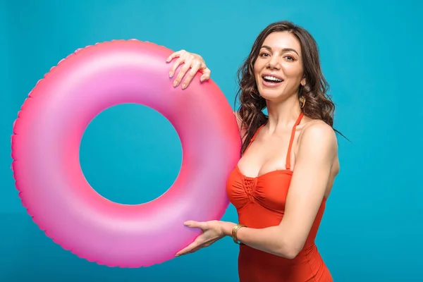 Pretty girl in swimsuit holding inflatable swim ring isolated on blue — Stock Photo