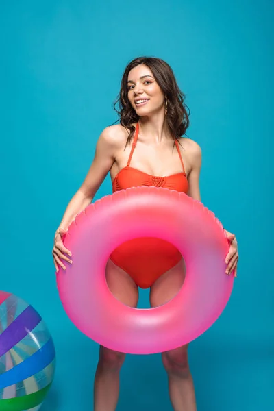 Pretty girl in swimsuit holding inflatable swim ring on blue — Stock Photo