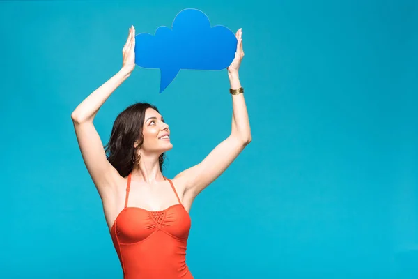 Smiling girl in swimsuit holding thought bubble isolated on blue — Stock Photo