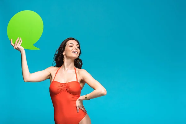 Menina encantadora em maiô segurando bolha discurso isolado em azul — Fotografia de Stock