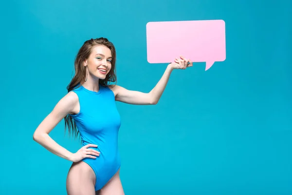 Charming girl in swimsuit holding speech bubble isolated on blue — Stock Photo