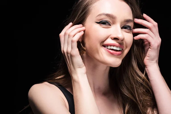 Attraente giovane donna in biancheria intima toccare i capelli e guardando la fotocamera con sorriso isolato su nero — Foto stock