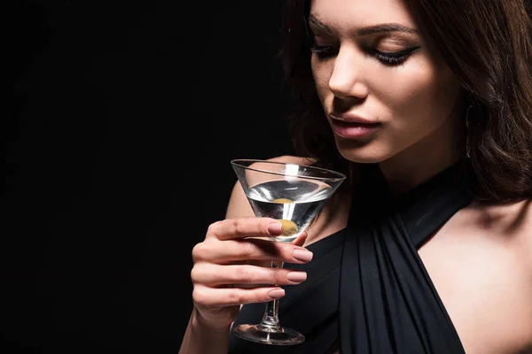 Bonita mujer con maquillaje sosteniendo vaso de martini con oliva aislado en negro - foto de stock