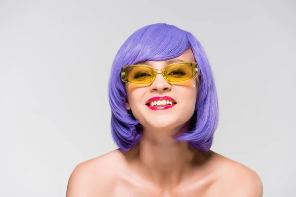 Hermosa chica sonriente en peluca púrpura y gafas de sol de moda aisladas en gris - foto de stock