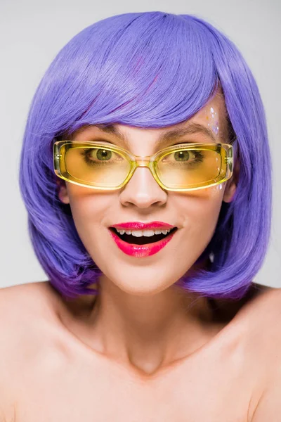 Bella ragazza sorpresa in parrucca viola e occhiali da sole isolati su grigio — Foto stock