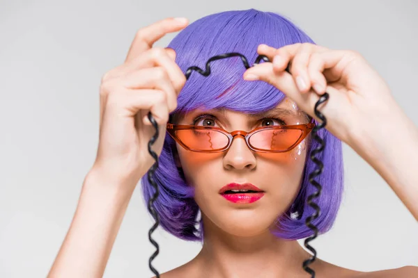 Woman in purple wig looking at cord of vintage telephone, isolated on grey — Stock Photo