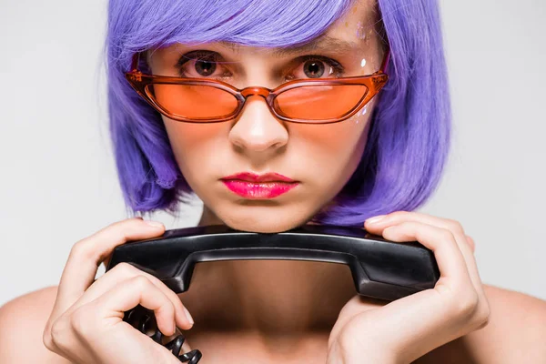 Mujer molesta en peluca púrpura sosteniendo teléfono retro, aislado en gris - foto de stock