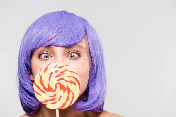 Happy girl in purple wig holding sweet lollipop, isolated on grey — Stock Photo