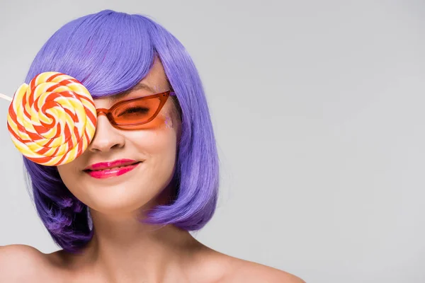 Sorridente ragazza in parrucca viola e occhiali da sole con dolce lecca-lecca, isolato su grigio — Foto stock