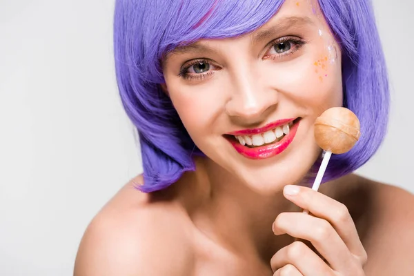 Bela menina sorridente em peruca roxa segurando doces doces, isolado em cinza — Fotografia de Stock