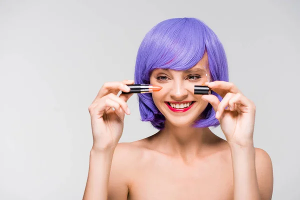 Hermosa chica desnuda en peluca púrpura celebración de lápiz labial aislado en gris - foto de stock
