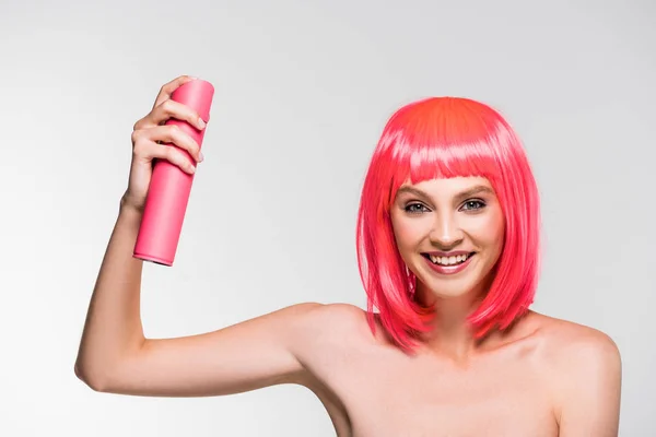 Mulher sorridente em peruca rosa segurando spray de cabelo, isolado em cinza — Fotografia de Stock