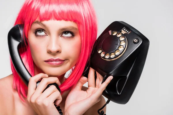 Belle femme ennuyée en perruque rose tenant téléphone rétro, isolée sur gris — Photo de stock