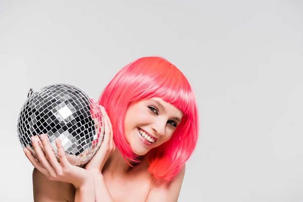 Lächelndes Mädchen in pinkfarbener Perücke mit Discokugel, isoliert auf grau — Stockfoto