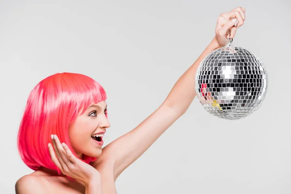 Excited girl in pink wig holding disco ball, isolated on grey — Stock Photo