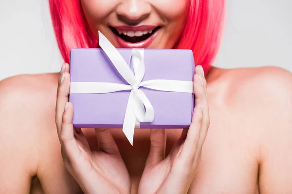 Обрезанный вид улыбающейся девушки в розовом парике с подарочной коробкой, изолированный на сером — стоковое фото
