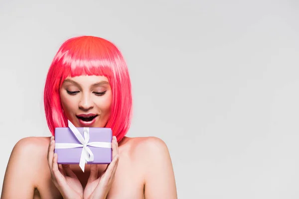 Excited beautiful girl in pink wig holding gift box, isolated on grey — Stock Photo