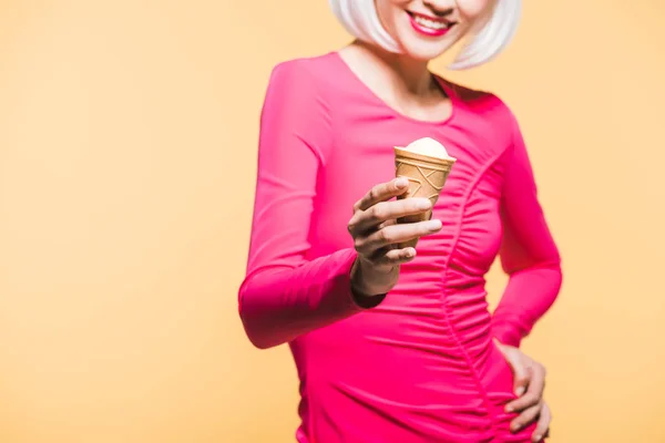 Vista cortada de menina sorridente em peruca branca comer sorvete, isolado em amarelo — Fotografia de Stock