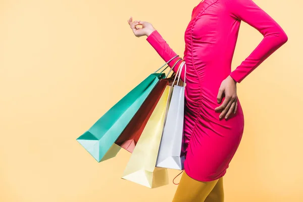 Vista recortada de la mujer con estilo con bolsas de compras, aislado en amarillo - foto de stock