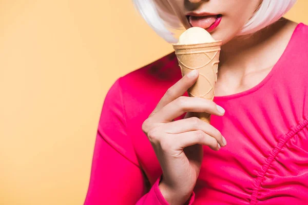 Обрізаний вид дівчини в білій перуці, що їсть морозиво, ізольований на жовтому — стокове фото