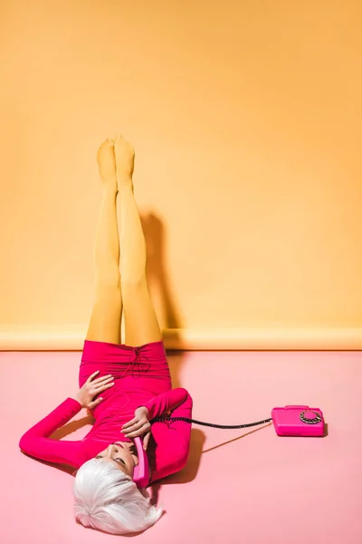 Fashionable young woman in white wig talking on retro telephone on yellow — Stock Photo