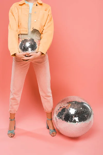 Обрезанный вид модной девушки, держащей дискотечный мяч на розовом фоне — стоковое фото