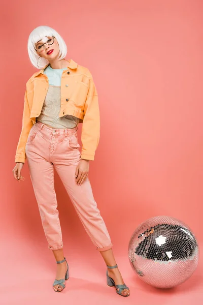 Menina bonita em peruca branca posando perto de bola de discoteca em rosa — Fotografia de Stock