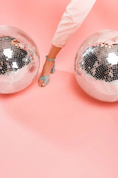 Vue recadrée de fille posant avec des boules de disco sur rose — Photo de stock