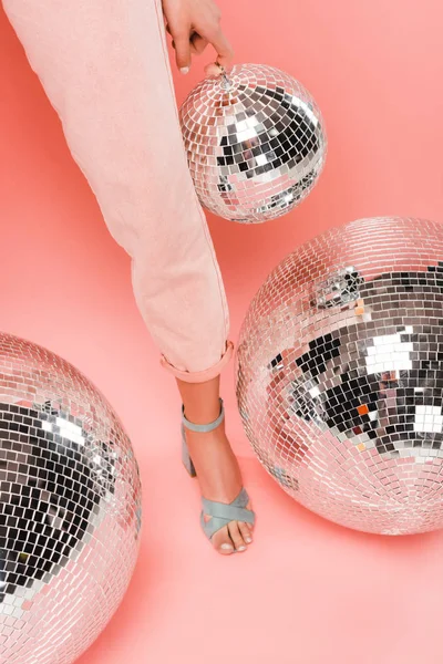 Vista parcial de chica elegante posando con bolas de discoteca en rosa — Stock Photo