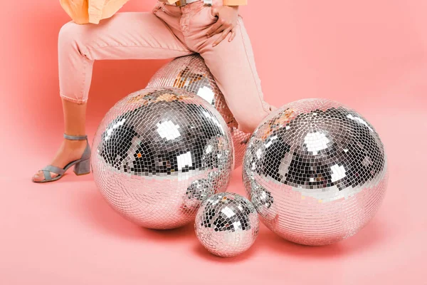 Частичный вид модной девушки, позирующей с шарами диско на розовом — стоковое фото