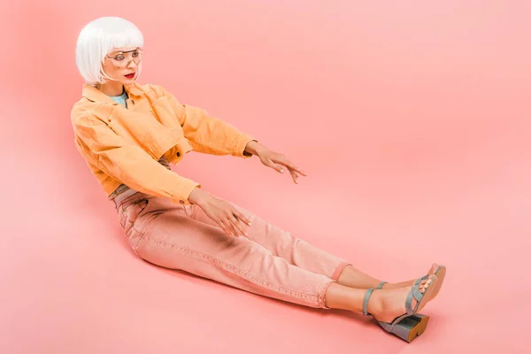 Attraktive Frau mit weißer Perücke posiert wie eine Puppe auf rosa — Stockfoto