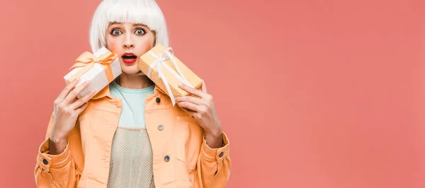 Fille choquée à la mode en perruque blanche tenant des boîtes-cadeaux, isolé sur rose — Photo de stock