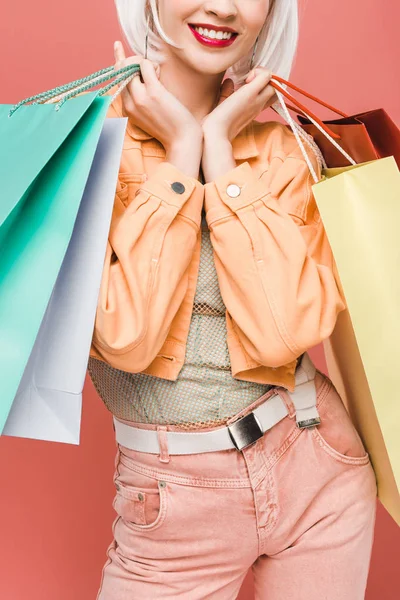 Vista recortada de chica feliz con bolsas de compras, aislado en rosa - foto de stock