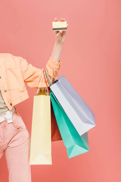 Vista recortada de chica con bolsas de compras y tarjeta de crédito, aislado en rosa - foto de stock