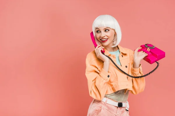 Beautiful young woman in white wig talking on retro telephone, isolated on pink — Stock Photo