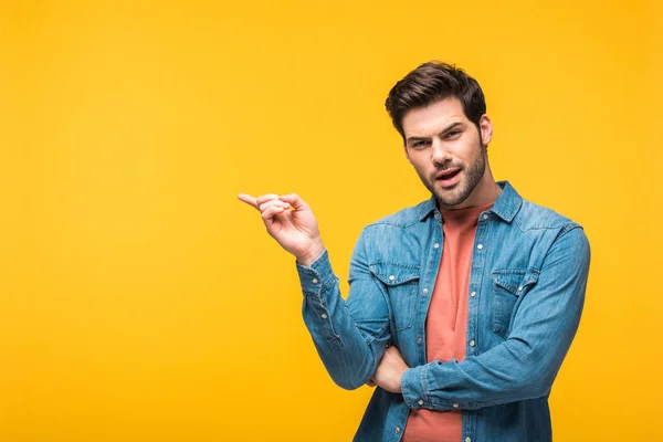 Verwirrter gutaussehender Mann zeigt mit dem Finger und schaut in die Kamera isoliert auf gelb — Stockfoto
